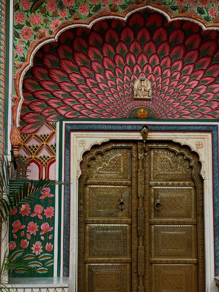 An ornate golden door with vibrant floral arches in Jaipur, RJ, India.